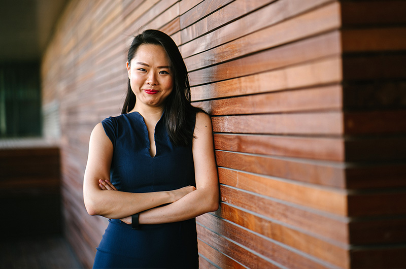 smiling woman with her arms crossed leaning against a wood-panelled wall