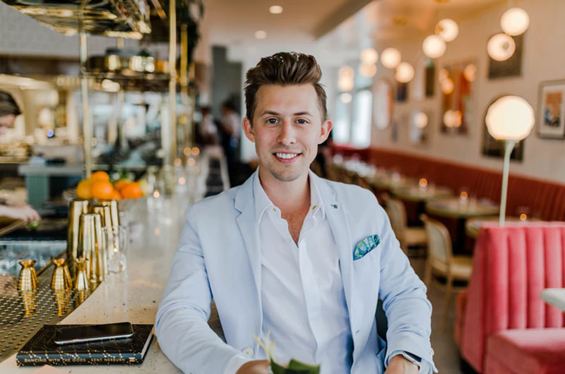 smiling man in a blue suit jacket sitting at a restaurant bar
